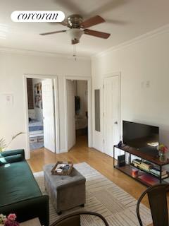 living room featuring crown molding, ceiling fan, and light hardwood / wood-style floors