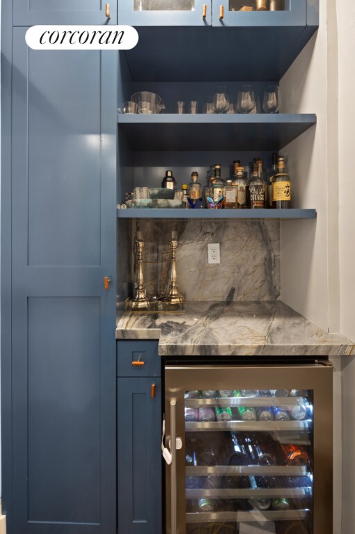 bar with blue cabinets and wine cooler