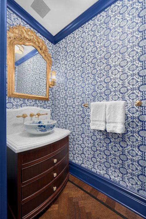 bathroom featuring parquet flooring, vanity, and ornamental molding