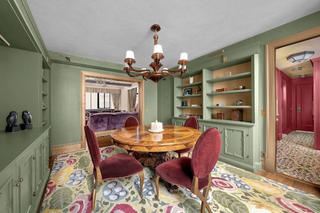 dining room with built in features, a chandelier, and light wood-type flooring