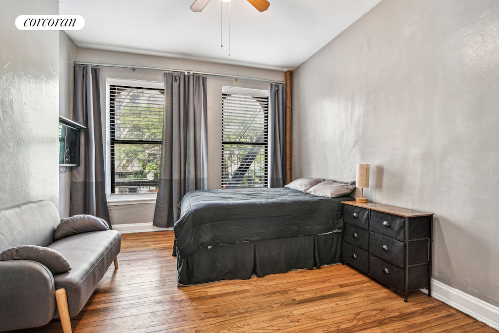 bedroom with ceiling fan, multiple windows, wood-type flooring, and lofted ceiling