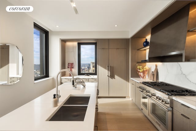 kitchen featuring exhaust hood, plenty of natural light, sink, and range with two ovens