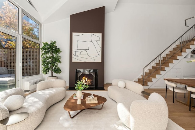 living room with radiator, hardwood / wood-style floors, and high vaulted ceiling