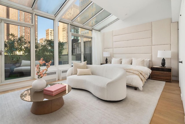 bedroom featuring vaulted ceiling, hardwood / wood-style floors, and a wall of windows