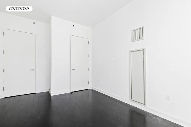 spare room featuring dark wood-type flooring and visible vents