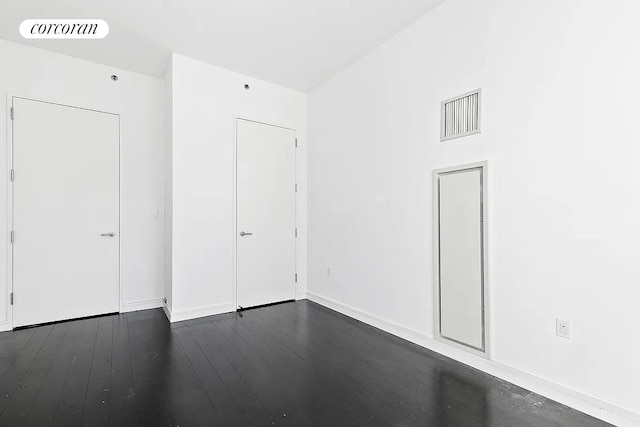 empty room with baseboards, dark wood-style floors, and visible vents