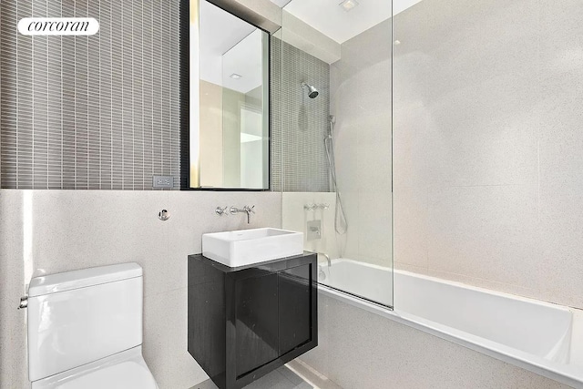 bathroom with tile walls, tub / shower combination, vanity, and toilet