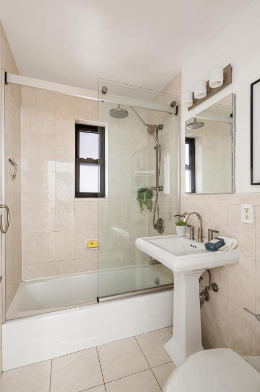 bathroom featuring toilet, combined bath / shower with glass door, tile patterned flooring, and tile walls