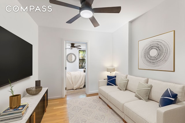 living room featuring ceiling fan, baseboards, and light wood-style floors