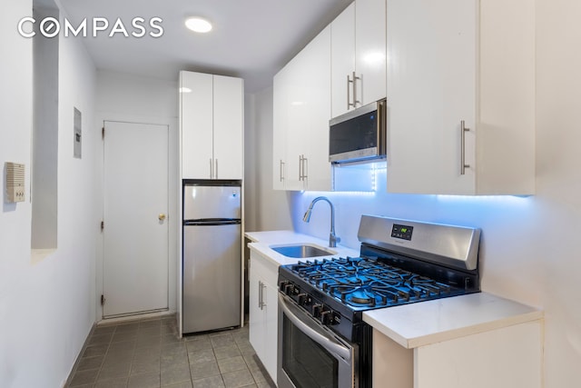 kitchen with light countertops, white cabinets, appliances with stainless steel finishes, and a sink