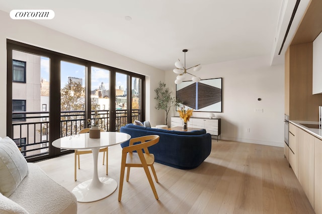 living room with a notable chandelier, baseboards, visible vents, and light wood finished floors