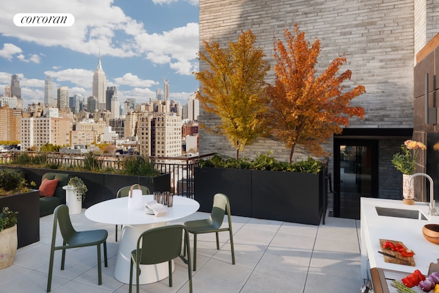 view of patio featuring outdoor dining space, a view of city, and a sink