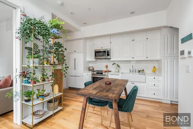 kitchen with stainless steel appliances, light hardwood / wood-style floors, white cabinets, and sink