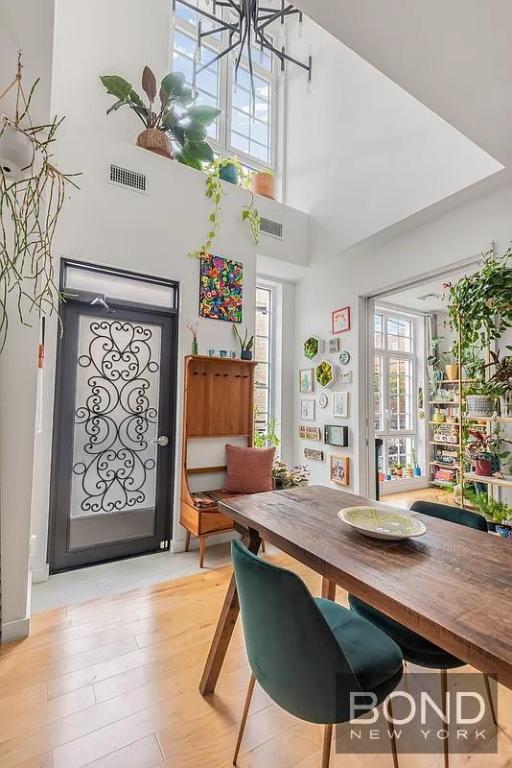 dining area with a healthy amount of sunlight, light hardwood / wood-style floors, and a high ceiling