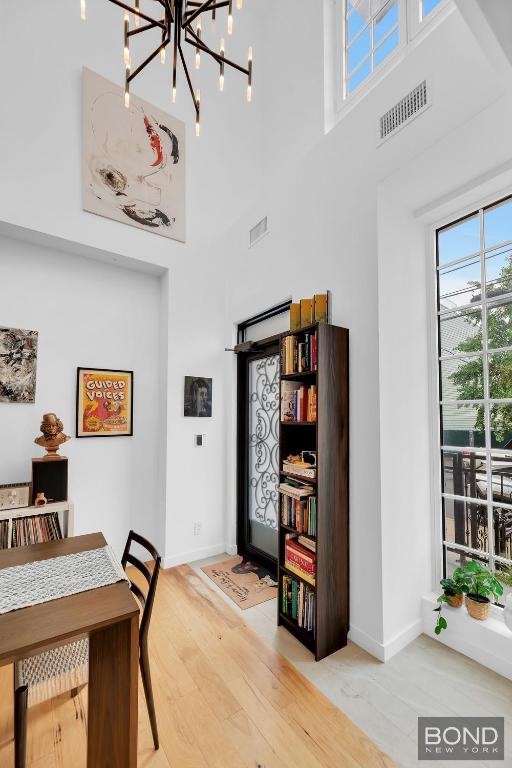 dining space featuring plenty of natural light, hardwood / wood-style floors, and a high ceiling