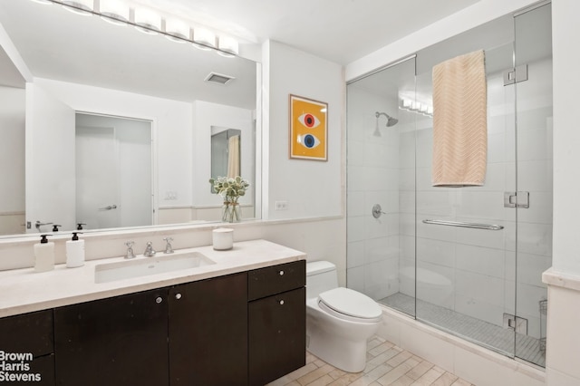 full bathroom featuring toilet, vanity, visible vents, and a shower stall