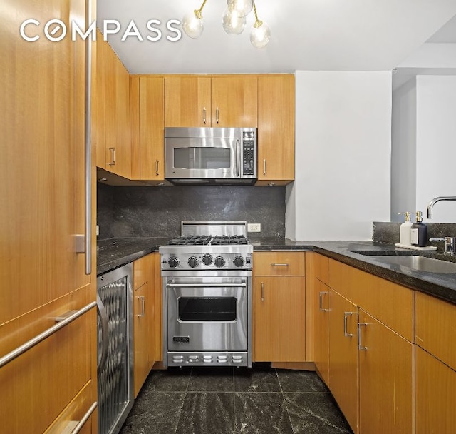 kitchen with stainless steel appliances, wine cooler, dark stone countertops, and a sink