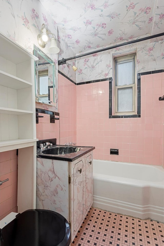 full bath with a tub to relax in, tile walls, vanity, and wallpapered walls