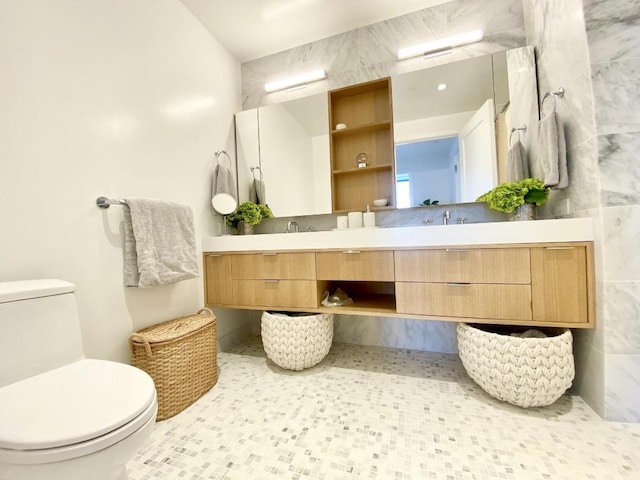 bathroom featuring double vanity, a sink, toilet, and tile walls