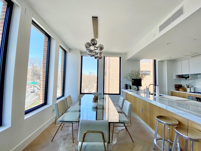 dining area with a notable chandelier, light wood-style floors, visible vents, and baseboards