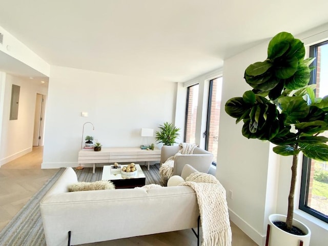 living area with plenty of natural light, electric panel, and baseboards