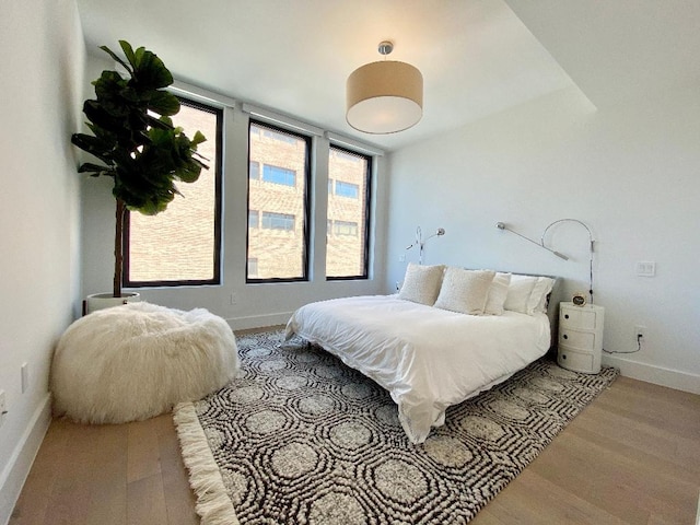 bedroom featuring light wood-style floors, multiple windows, and baseboards