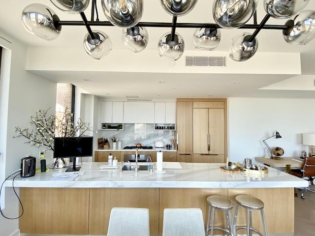 kitchen featuring visible vents, backsplash, light brown cabinetry, white cabinetry, and a peninsula