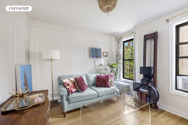 living area with radiator, wood finished floors, cooling unit, and baseboards