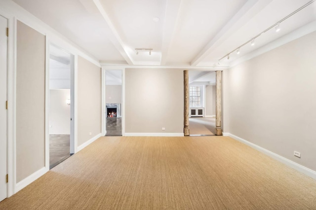 unfurnished room with light carpet, rail lighting, baseboards, and a lit fireplace