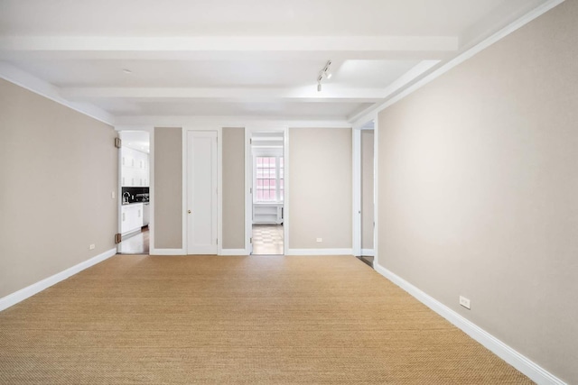 empty room with light carpet, beamed ceiling, and baseboards