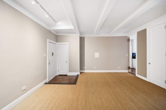 empty room featuring beam ceiling, rail lighting, baseboards, and wood finished floors