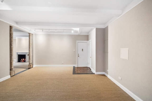 interior space with baseboards, a lit fireplace, track lighting, and carpet flooring