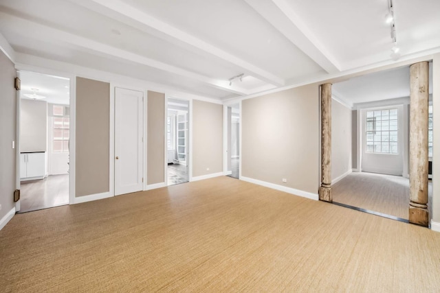 interior space featuring carpet flooring, beamed ceiling, rail lighting, and baseboards