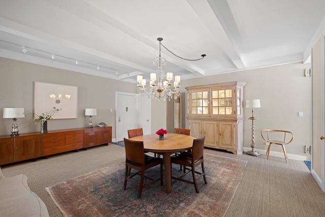 dining area with baseboards, beam ceiling, rail lighting, a notable chandelier, and light colored carpet