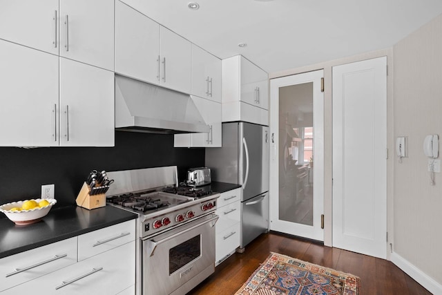 kitchen with under cabinet range hood, dark wood-type flooring, dark countertops, and appliances with stainless steel finishes