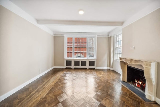 unfurnished living room with beamed ceiling, baseboards, and a warm lit fireplace