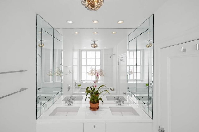 full bathroom featuring double vanity, recessed lighting, a shower with door, and a sink