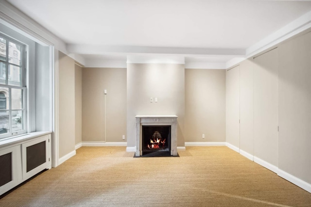 unfurnished living room featuring a wealth of natural light, a fireplace with flush hearth, and light colored carpet