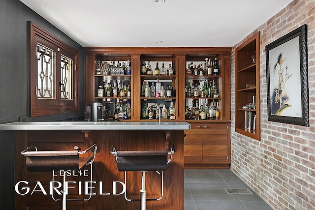 bar with dark tile patterned floors and brick wall