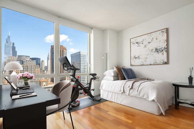 bedroom with wood-type flooring and a wall of windows