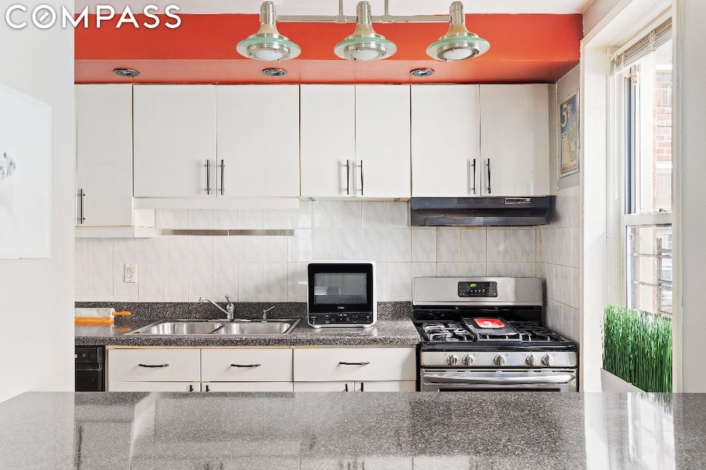 kitchen with decorative backsplash, white cabinets, stainless steel range with gas cooktop, and sink