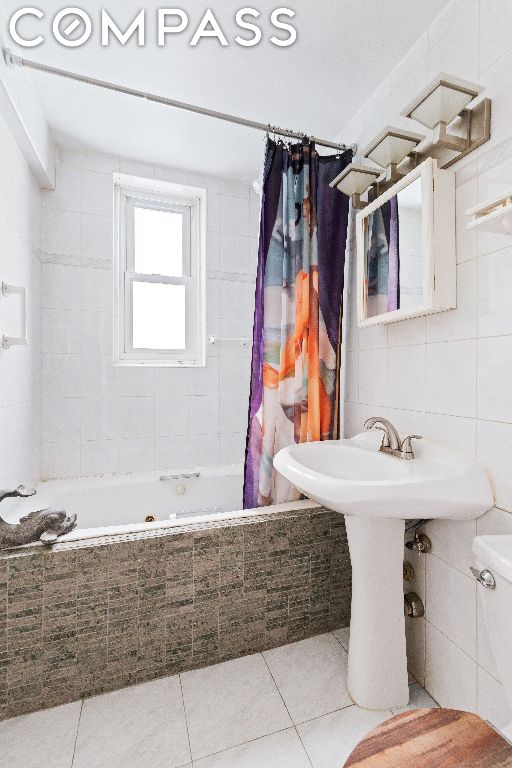 bathroom featuring toilet, tile patterned flooring, tile walls, and shower / bath combo