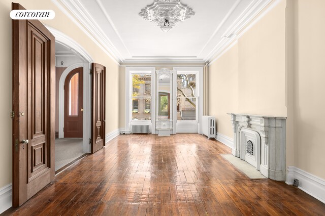 unfurnished living room with crown molding, dark hardwood / wood-style flooring, and radiator