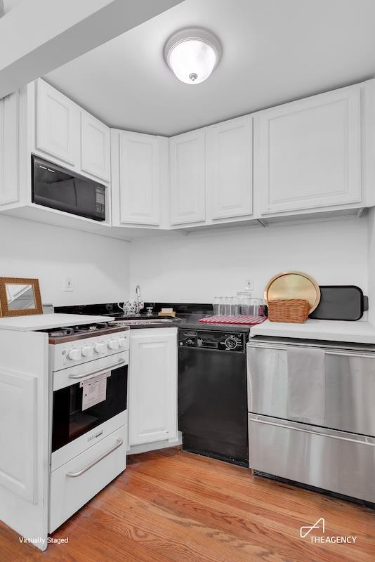 kitchen with black dishwasher, built in microwave, light wood-type flooring, white cabinetry, and a sink