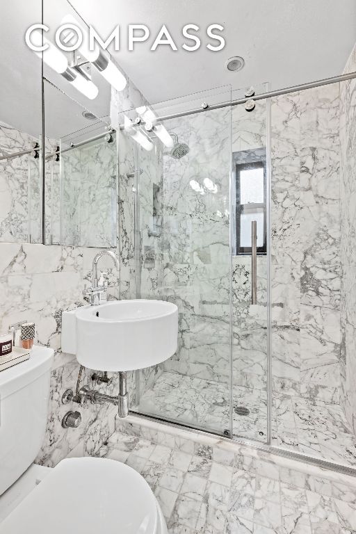 bathroom with tile walls, sink, toilet, and walk in shower