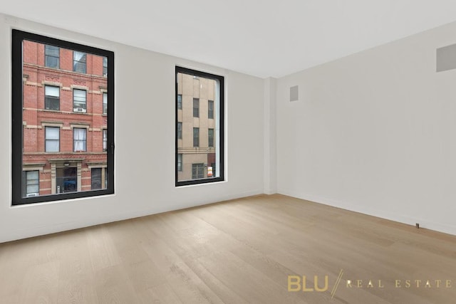 spare room with visible vents, light wood-style flooring, and baseboards