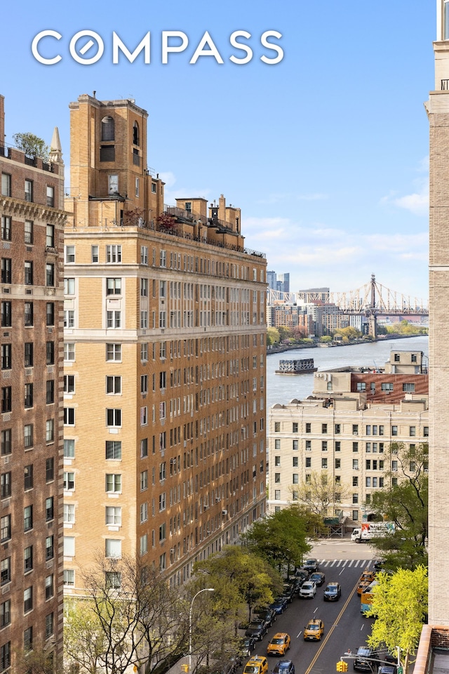 view of property with uncovered parking, a city view, and a water view