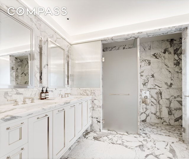 bathroom featuring a marble finish shower, double vanity, marble finish floor, tile walls, and a sink