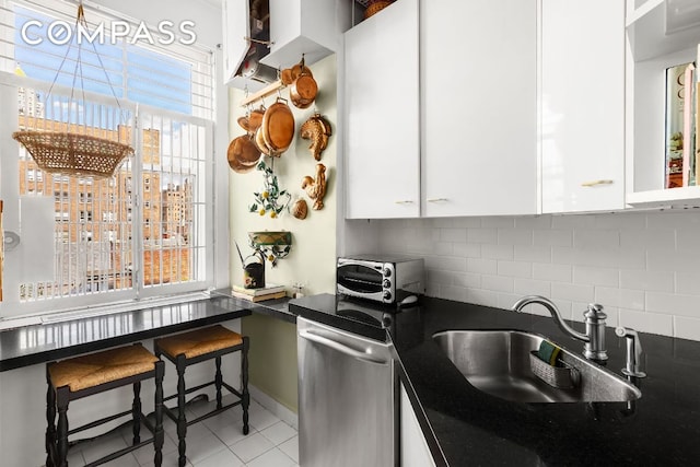 kitchen featuring sink, decorative backsplash, dishwasher, and white cabinets