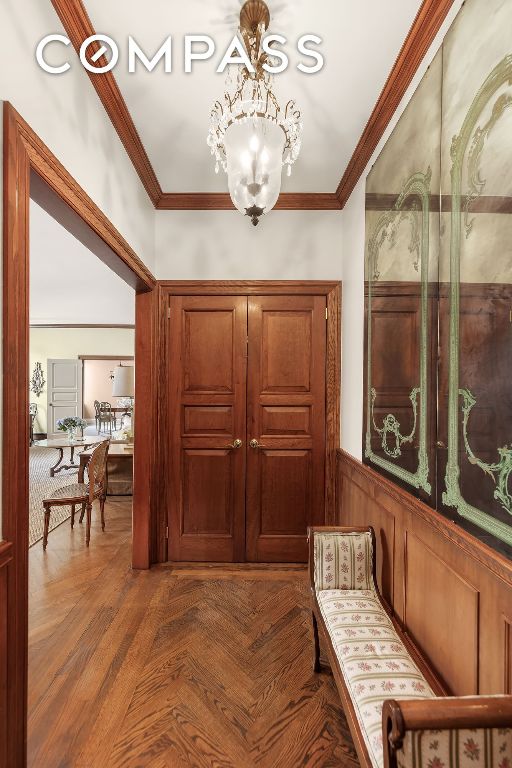 interior space featuring parquet flooring, ornamental molding, and a notable chandelier